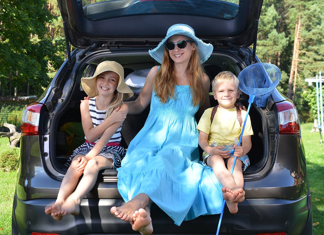 About Our Agency - Mother and Kids Sitting in Back of Car at a Park
