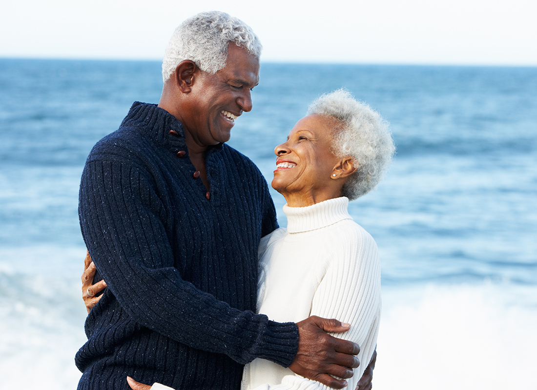 Medicare - Senior Couple on Beach Smiling at Each Other